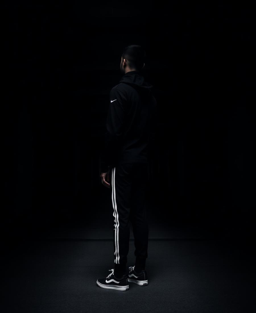 Atleta de espaldas con ropa deportiva negra en arquitectura urbana oscura