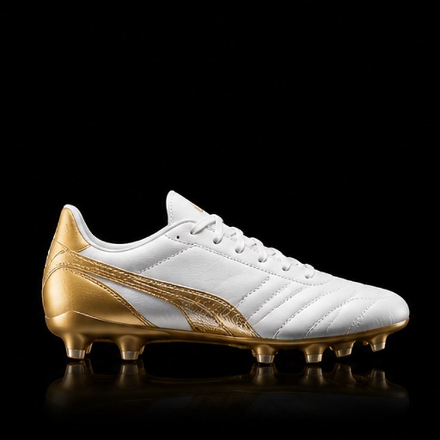 Tachón de fútbol blanco con detalles dorados sobre fondo negro