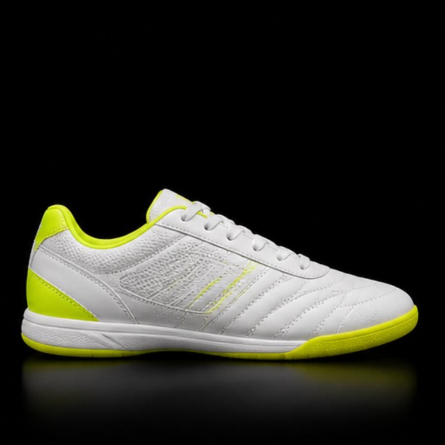 Zapatilla de fútbol sala blanca con detalles amarillo neón sobre fondo negro